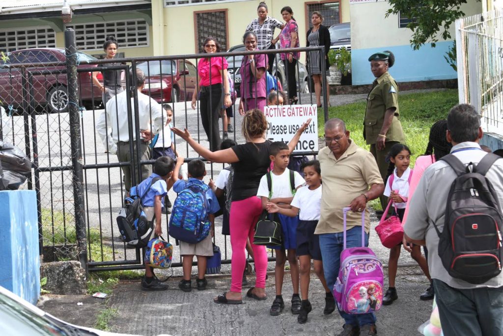 SCHOOL AS NORMAL: Parents collect their children yesterday outside the Jordan Hill Presbyterian Primary school in Princes Town, a day after a teacher was robbed at gunpoint of her van.
