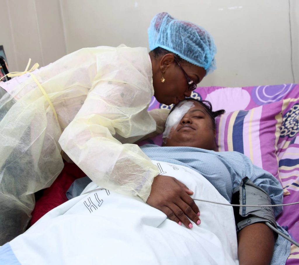 Brenda Henry kisses her daughter Faith Haynes after successful cornea replacement surgery yesterday at the San Fernando General Hospital.