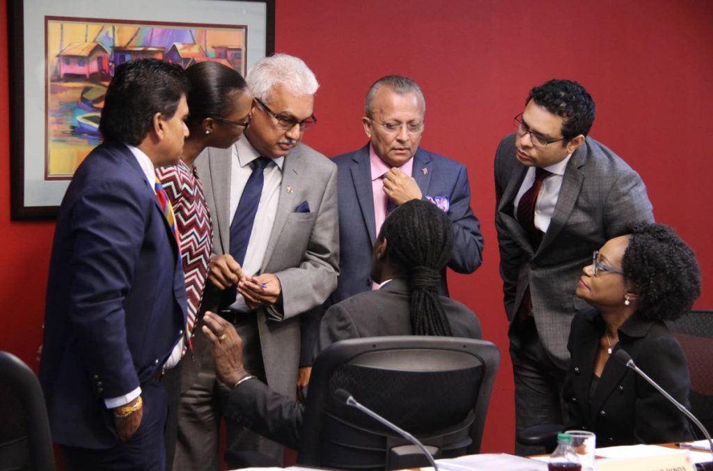 Members of Parliament’s Special Select Committee (standing from left) Dr Roodal Moonilal, Nicole Olivierre, Terrance Deyalsingh, Ganga Singh, and Randall Mitchell huddle around chairman Fitzgerld Hinds Parliament secretary Jacqui Sampson (right) looks on.