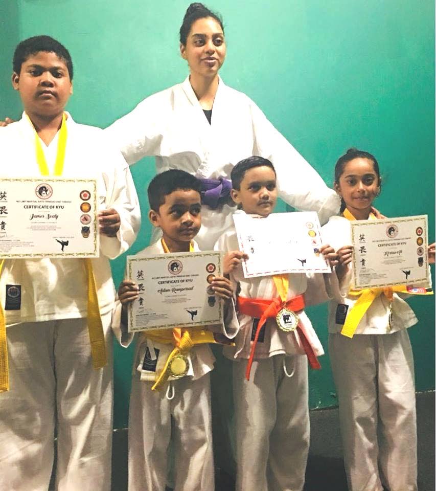 Members of No Limit Martial Arts in Rio Claro display certificates after earning belt promotions.