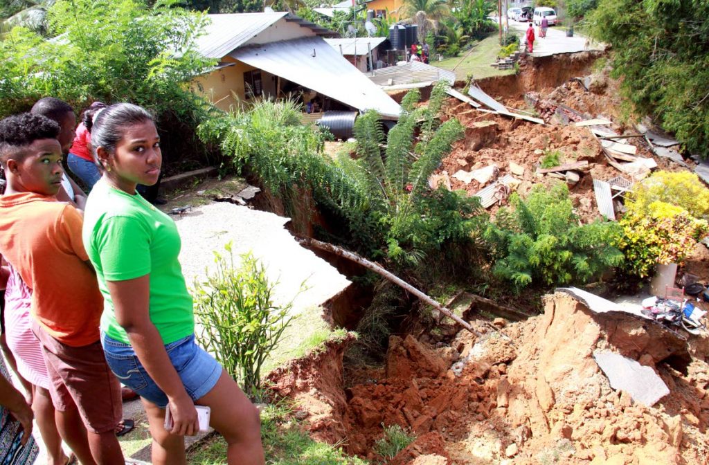 COLLPASE: Residents stand near the area in Bamboo Village, Cedros where a sink hole on Monday 
caused a house to and sections of the roadway to collapse.