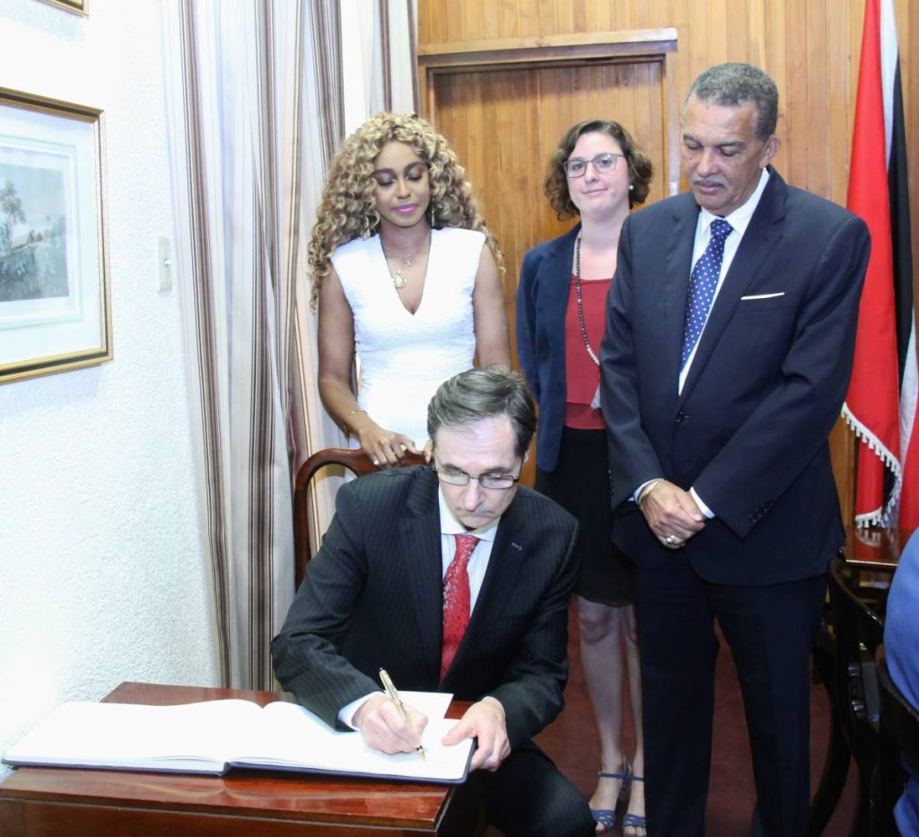 YOUR EXCELLENCY: New Ambassador of France to Trinidad and Tobago Serge Lavroff signs the visitor's book at the Office of the President yesterday while his wife Caroline (left), Deputy Head of Mission Solène Crinière (centre) and President Anthony Carmona look on. 