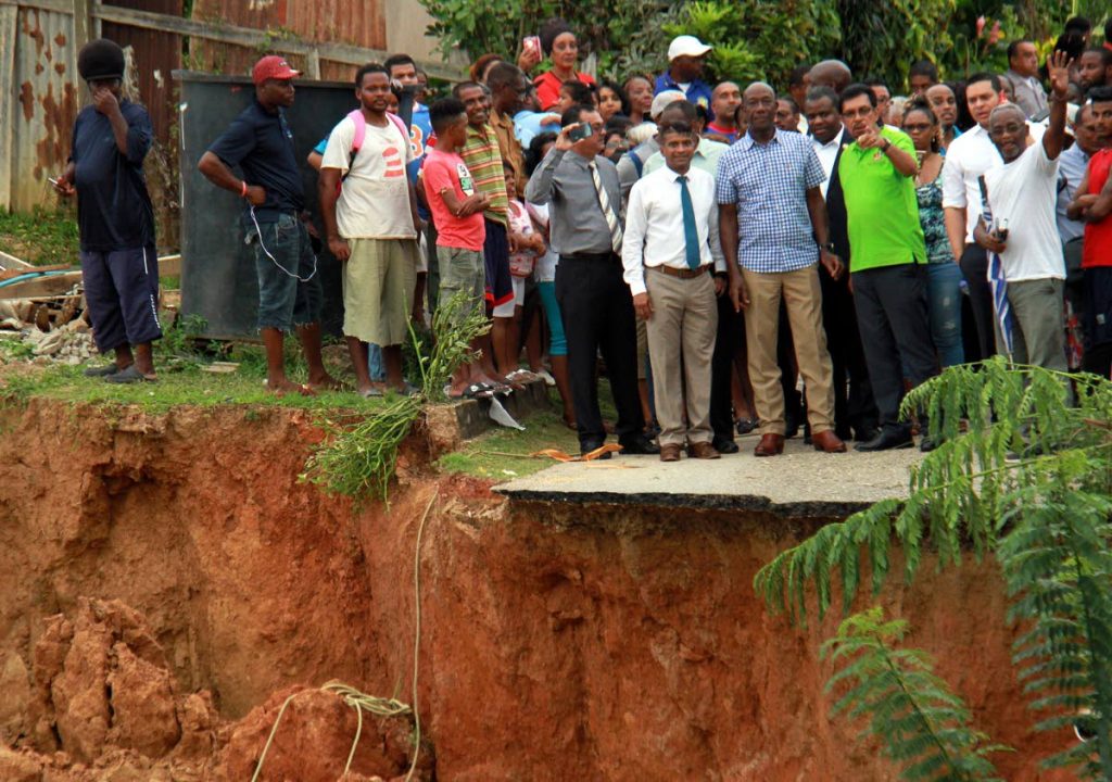 ON THE EDGE: Prime Minister Dr Keith Rowley (in plaid shirt) surveys the damage yesterday in Bamboo Village, Cedros.