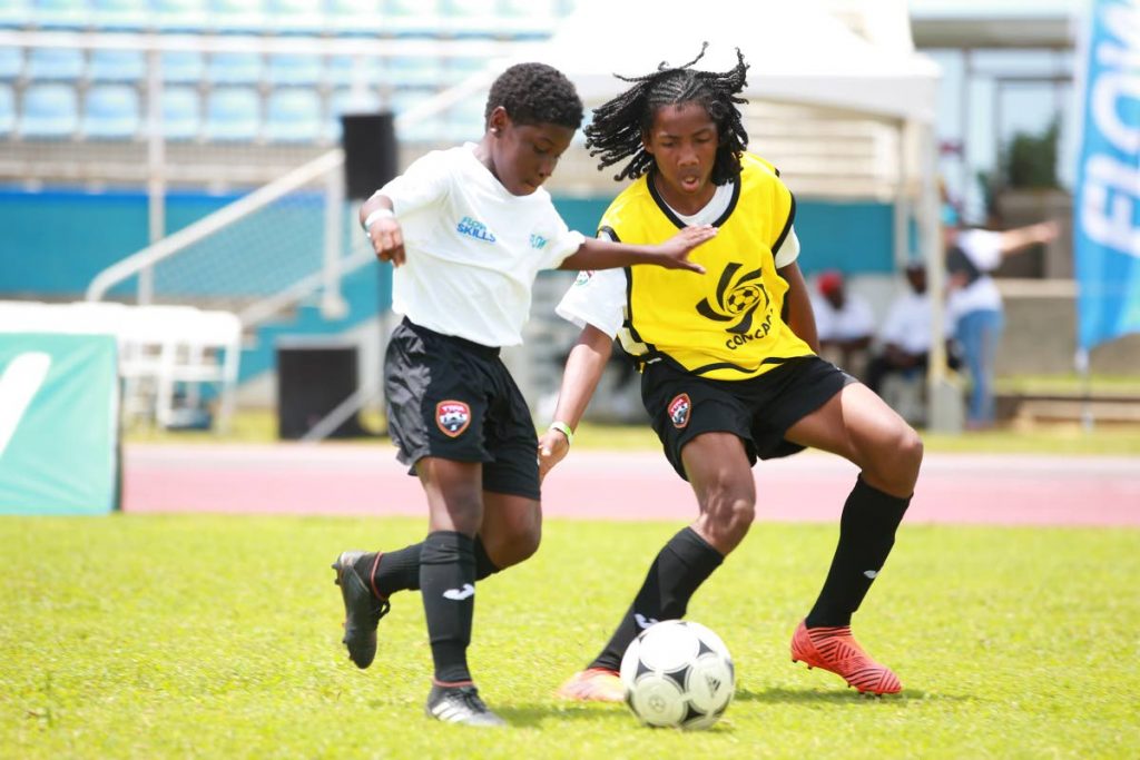 Abdu Quddos Hypolite,left, attempts to dribble past Molik Khan during the FLOW Ultimate Football Experience FLOW Skills Competition at the Ato Boldon Stadium, Couva yesterday.