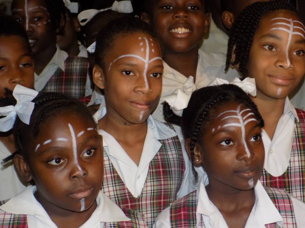 Students of the Belmont Girls' Primary School wearing traditional African face paint pose for a photo in the lobby of the Digicel Imax theatre yesterday before their viewing of the Black Panther movie.