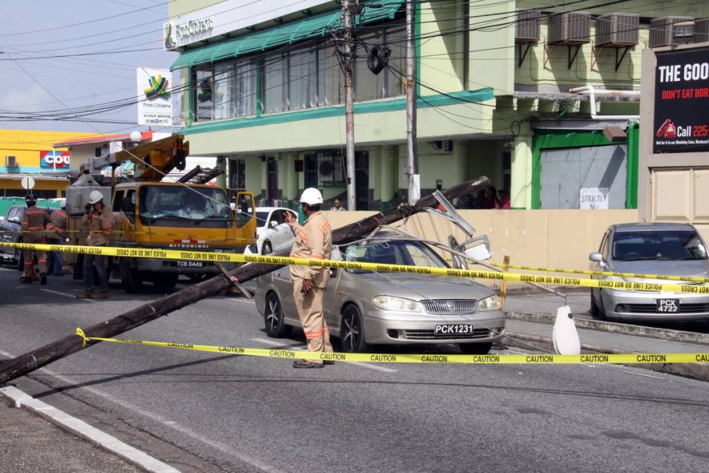 CRASH SCENE: Hollis Avenue in Arima had to be cordoned off for several minutes yesterday after a rotting utility pole fell on this car.