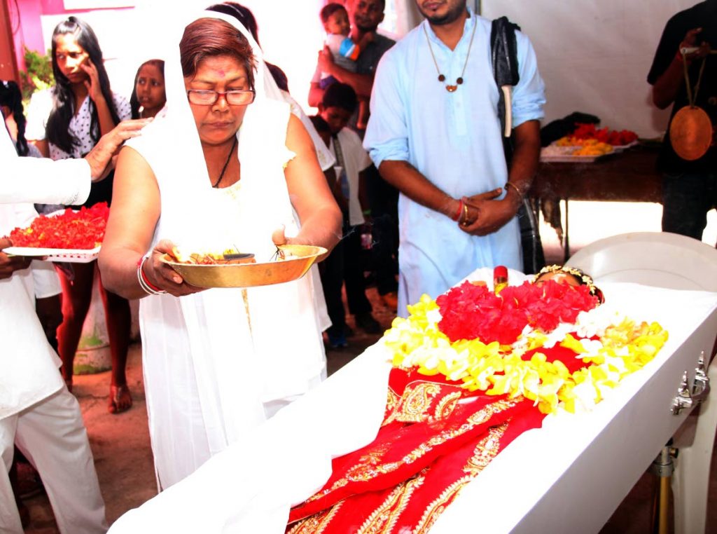 FOR MY DAUGHTER: Deomattee Madoo performs a Hindu ritual over her daughter Rachel Madoo’s body at her funeral yesterday at the family’s home in Chaguanas.