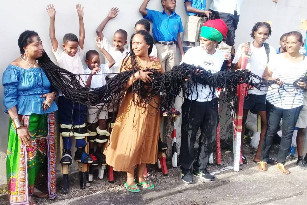 Trini-born American Asha Mandela, who is in the Guinness Book of World Records for having the longest hair in the world, gets some assistance to have her locks stretched for this photo yesterday in San Fernando.