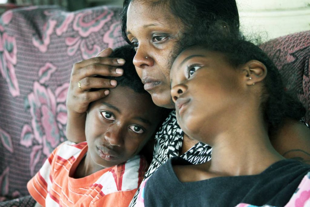TEARS AFTER MURDER: Radica Pooran comforts
her son Kayron and
daughter Kyley yesterday at their Gasparillo home a day after the children’s father and Radica’s common-law husband Sgt Ken Palmer was shot dead during an
altercation with a group of men. See Page 11A.PHOTO BY JEFF K MAYERS