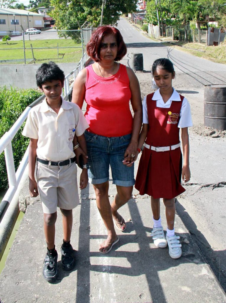 DANGER WALK: Suzie Ramdeo and her children Adrian and Areanna walk along a bridge which they and other Barrackpore residents fear could collapse at any time. PHOTO BY ANIL RAMPERSAD