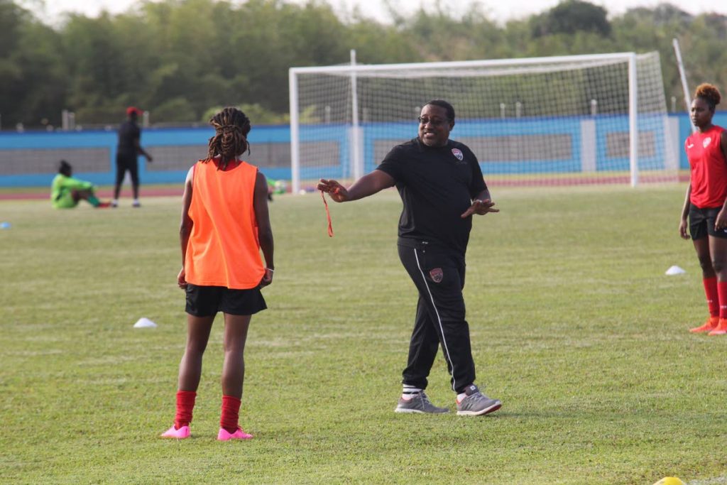 National women’s team coach Jamaal Shabazz (second from right) speaks to Patrice Superville during a training session yesterday at the Ato Boldon Stadium, Couva.