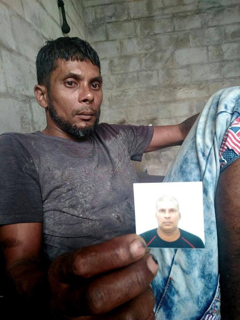 HE’S DEAD: Shivanand Rampersad holds a photo of his 47-year-old brother Roland Rampersad who was killed in an accident on Tuesday night.