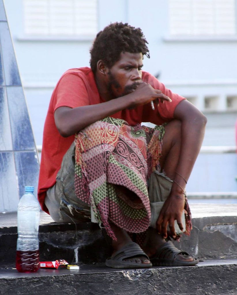 A homeless man sits on Marcus Gavey monument, Harris Promenade, San Fernando.