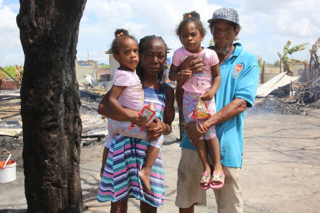 Homeowners Donna Coombs-Smith and Christopher Smith with their twin granddaughters Waynika (left) and Waynisha Hosten at the site of their home which was destroyed by fire on Thursday.