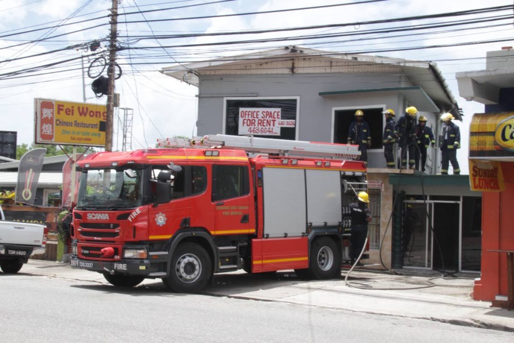 QUICK ACTION: Fire officers respond to a secondary report of smoke coming from an early morning blaze at Fei Wong Chinese Resturant, on the business district along Mucurapo Road, yesterday. PHOTO BY ROGER JACOB