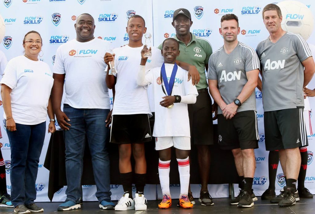 2017 winners Nathan Skeete (third from left) and Brian Burkett (centre) pose with their medals along with Cindy Ann Gatt, director of marketing at Flow (left), Neil Cochrane, Caribbean Football Union general secretary (second from left), football legend Dwight Yorke (third from right), and Manchester United football academy coaches Damien Sweeny (second from right) and Andy Robinson.