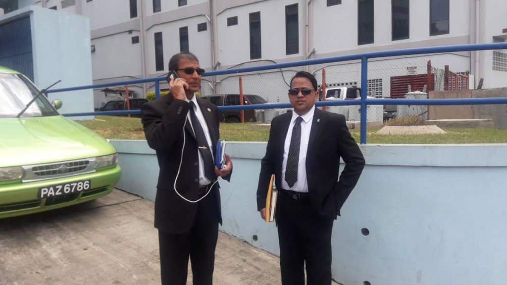 WAITING: Head of Fraud Squad Snr Supt Totaram Dookie, left, and Sgt Vinelle Bassarath outside the San Fernando Courts on Monday.