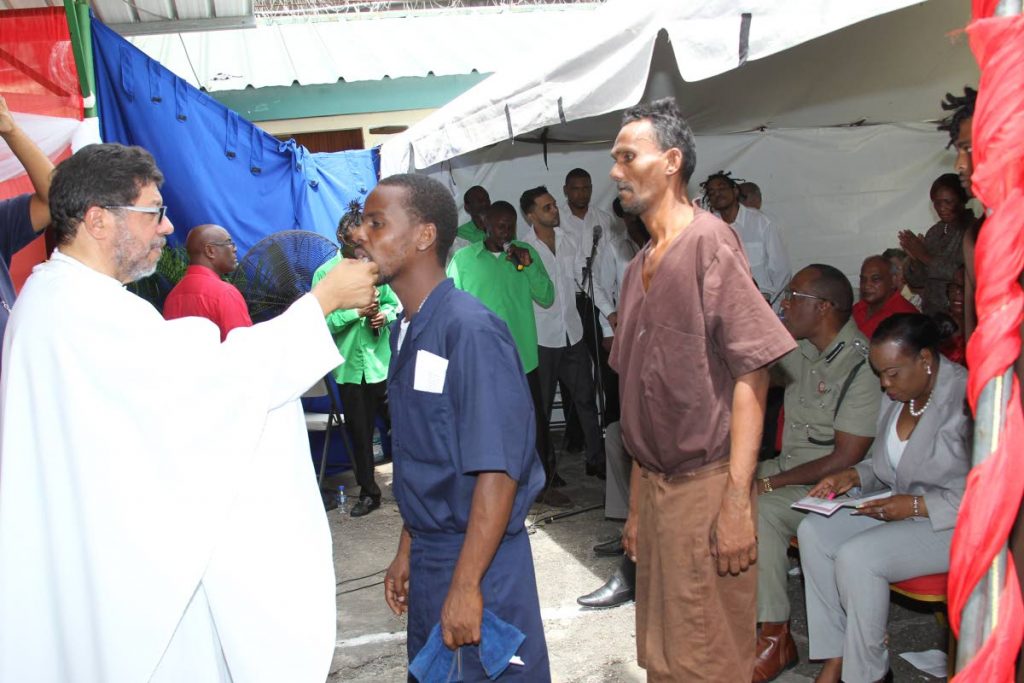 BODY OF CHRIST: Prisoners receive communion from RC Archbishop Jason Gordon during a service at the Golden Grove prison in Arouca yesterday.   PHOTO BY RATTAN JADOO