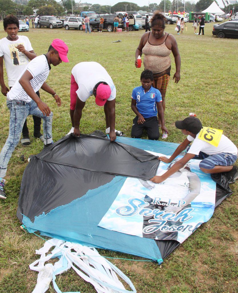 N MEMORY: Relatives of murdered Sarah Joseph put the finishing touches on a mad bull kite with her photo at the Queen’s Park Savannah yesterday.   PHOTO BY ANGELO M MARCELLE