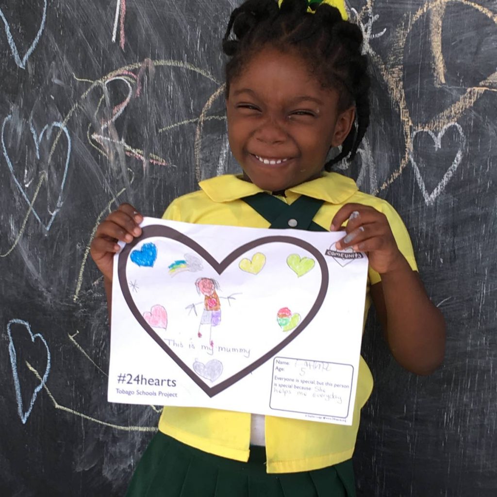 A girl holds up a 24 Hearts  drawing of someone she thinks is special.