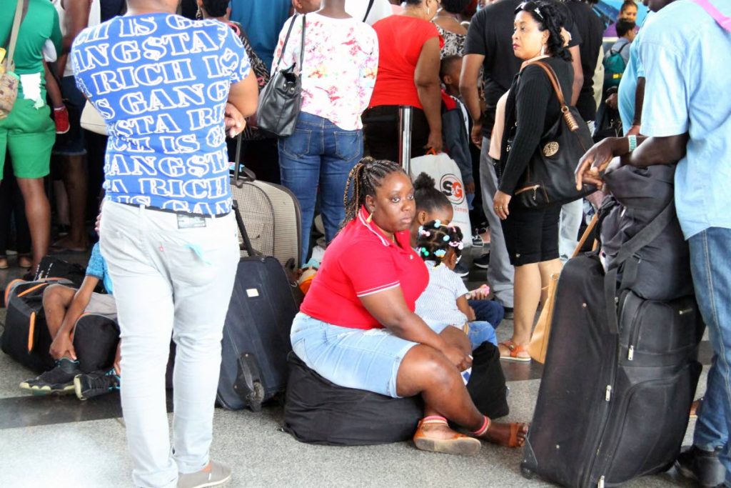 On the floor: A woman with children sit on their luggage among crowded lines as passengers checked in for flights to Tobago at Piarco International Airport yesterday. PHOTO BY SUREASH CHOLAI