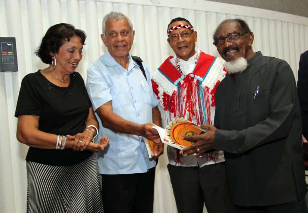 BOOK FOR CHALKIE: First Peoples chief Ricardo Bharath Hernandez, 2nd from right, looks on as calypsonian Dr Hollis “Chalkdust” Liverpool, right, holds a copy of the  book’ Re-igniting the Ancestral Fires’. Also in photo from left are Jassie Singh and Dr Brinsley Samaroo. PHOTO BY SUREASH CHOLAI
