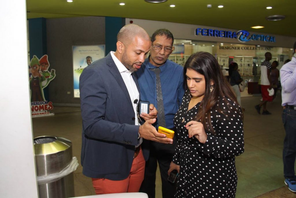 TOP TECHNOLOGY: Samsung sales manager(T&T) Jarrod Best-Mitchell (left) explains some of the features of the new Samsung S9 to Lisa and Robbie Maharaj of R&J Cell Tech, Trincity Mall, Trincity yesterday.  PHOTOBY ANGELO M MARCELLE