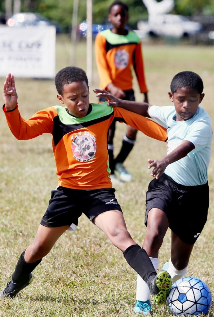 A Queen’s Park Under-12 player, right, tussles with his T&T Maestros opponent in a Republic National Youth League match yesterday at the Queen’s Park Savannah, Port of Spain, yesterday.