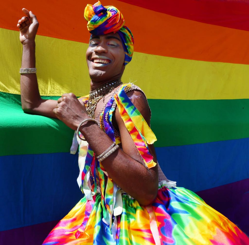 RAINBOW PRIDE: A member of the LGBTQI community pose in front of a rainbow flag at Woodford Square, Port of Spain, on Thursday after a High Court judge ruled that this country’s buggery laws were unconstitutional. PHOTO BY AZLAN MOHAMMED