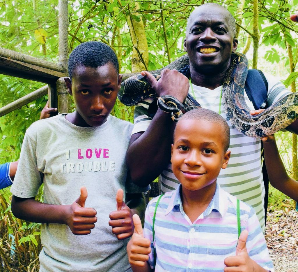 Educational Coordinator of Environment Tobago, Barry Lovelace, handles a snake alongside members of the camp. 