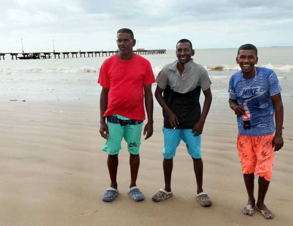 From Left Awarnath Hajarie, Nicholas Nanlal and Shammi Seepersad share a light moment on Cedros beach after being processed by local coast guard and Immigration officers yesterday. PHOTO BY AZLAN MOHAMMED