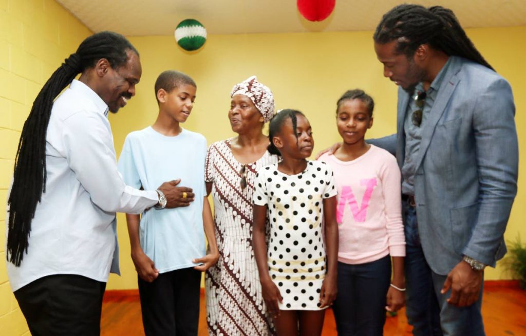 PEP TALK: Minister in the Office of the AG Fitzgerald Hinds (left) gives some sound advice to SEA student Tyler Williams as Ena Garcia, who said a prayrer for the children looks on. At right, Laventille East/Morvant MP Adrian Leonce chats with Ruth Thompson and Maurina Mc Donald. PHOTO BY AZLAN MOHAMMED