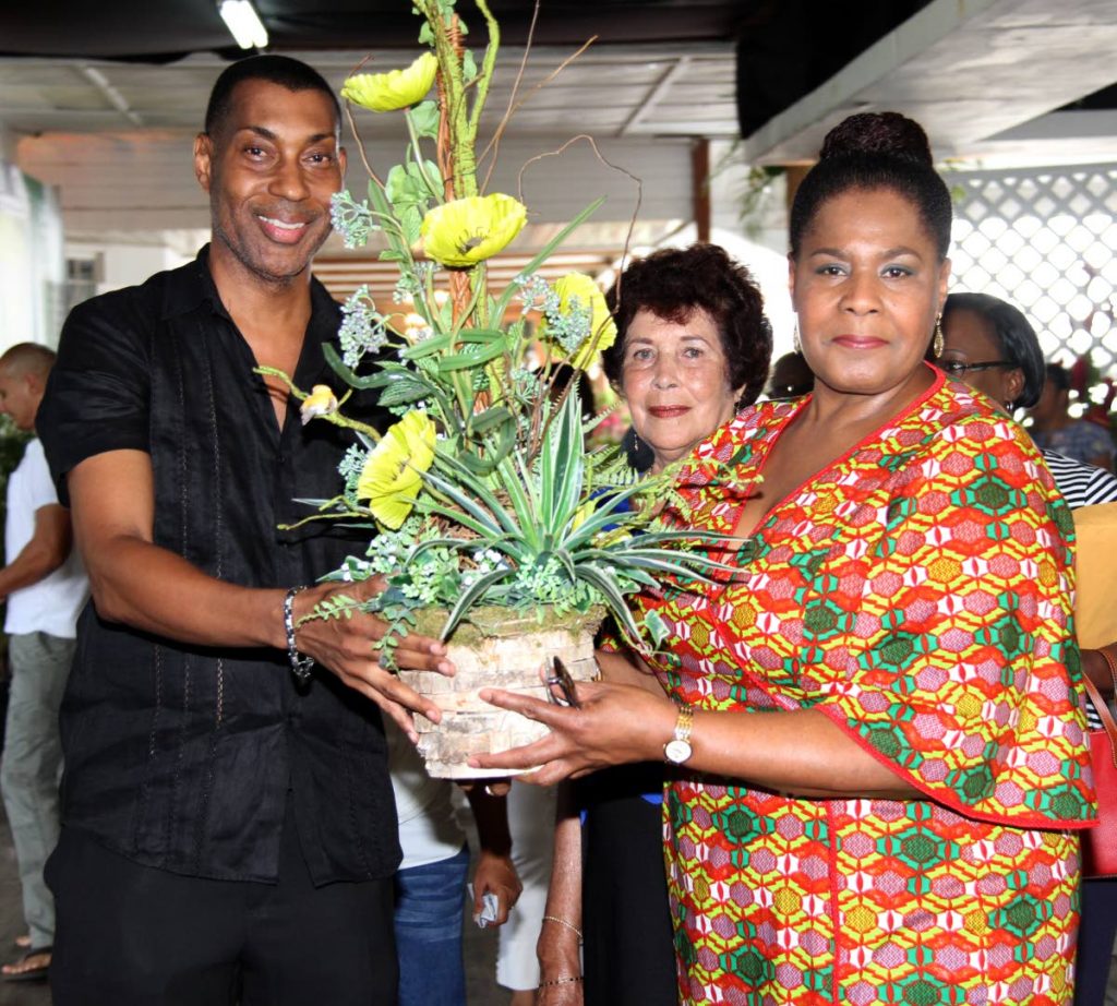 Floral presentation: Bernard Beckles, owner of La Tropicale flower shop, presents President Paula-Mae Weekes with an arrangement named Birdnesting as acting president of the Horticultural Society Chanardai Ramkissoon looks on at Trinidad Country Club, Maraval.