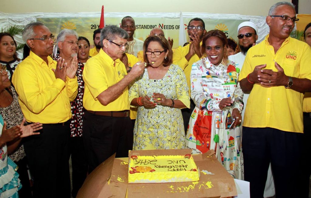 Celebration time: UNC deputy leader Jearlean John and Couva South MP Rudy Indarsingh, both at right, and party members applaud as Dr Gregory Bissessar shares a piece of cake with his wife Opposition Leader Kamla Persad-Bissessar during an interfaith service celebrating the 29th anniversary of the UNC at the Couva South Multi-Purpose Hall yesterday. PHOTO BY ANIL RAMPERSAD.