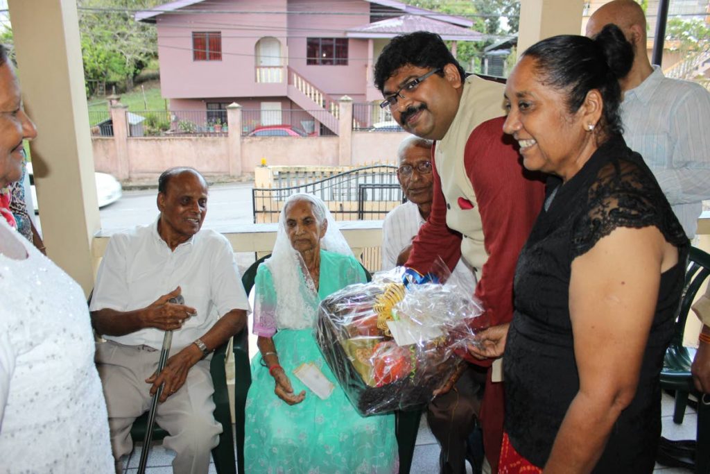 Centenarian Senkuari Basdeo, seated, receives a hamper from  Biswadip Dey, Indian High Commissioner to TT.