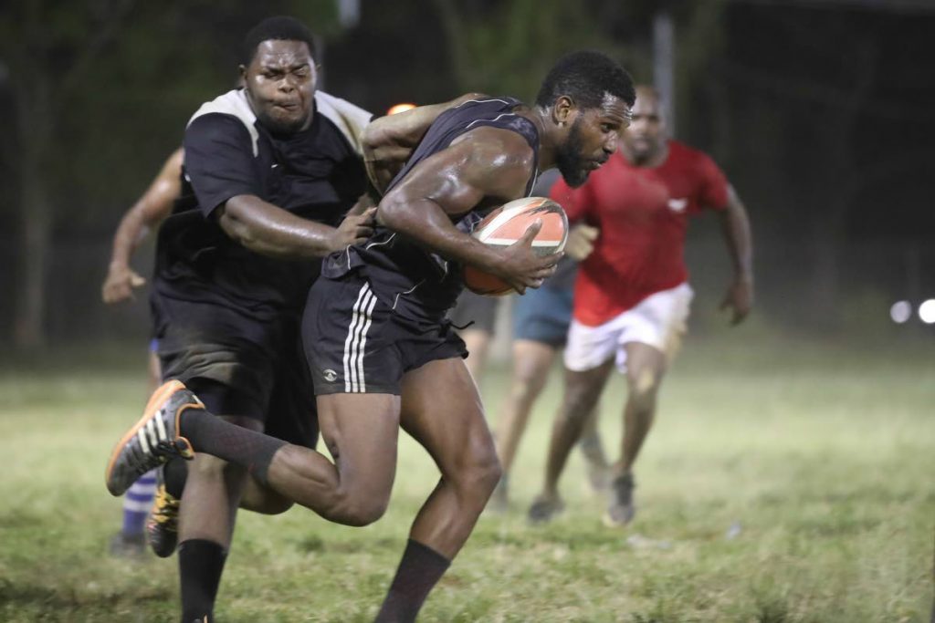 National rugby player James Phillip, right, shrugs off a challenge from a teammate during a training session on Monday at President’s Grounds, St. Ann’s. TT are preparing for the Rugby Americas North (RAN) Championships later this month.