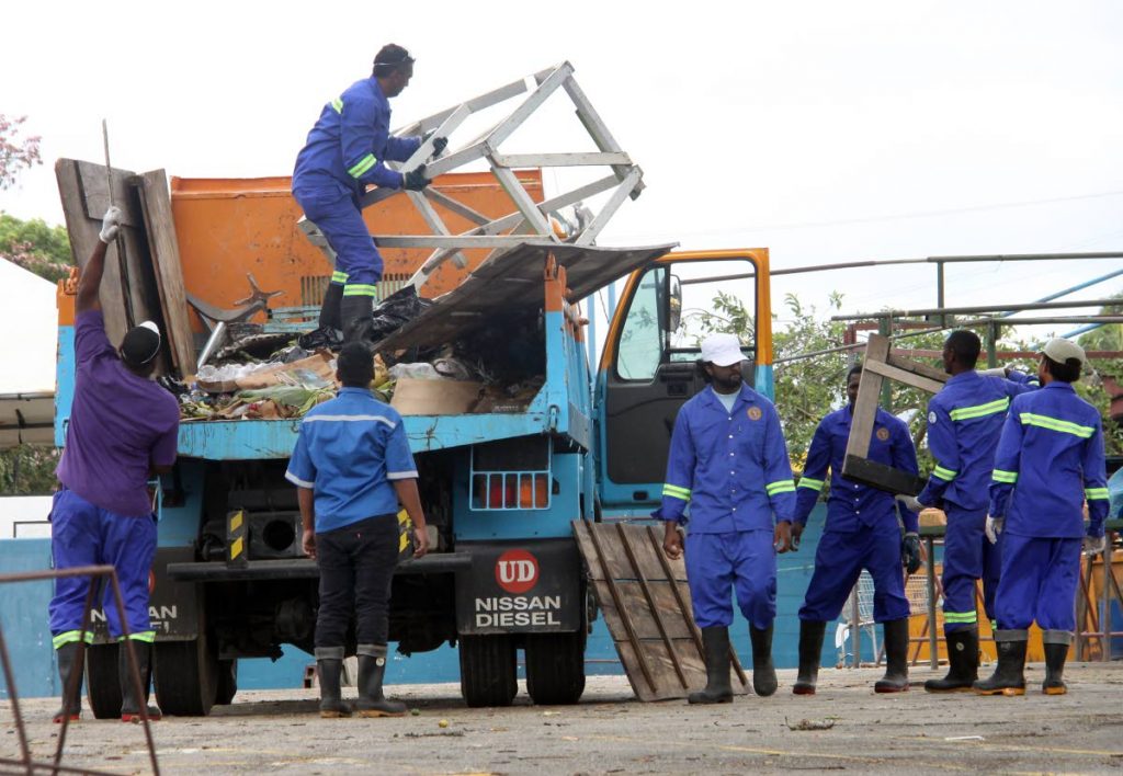 Arima Borough Corporation workers remove stalls and garbage from the Arima market yesterday.