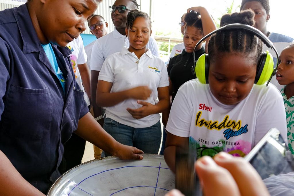 Shell Invaders youngster Mya Clark hammers a note on a bass pan under the direction of Starlift Workshop instructor Roisha Edward.

