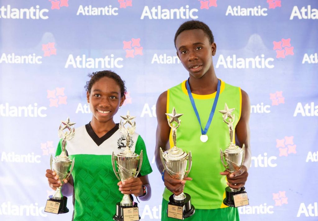 Cumana AC’s Kevin Robinson, right, and Kaleigh Forde from Dunross Prep, show off their trophies after winning the male and female divisions of the Atlantic 3K road race on Wednesday.