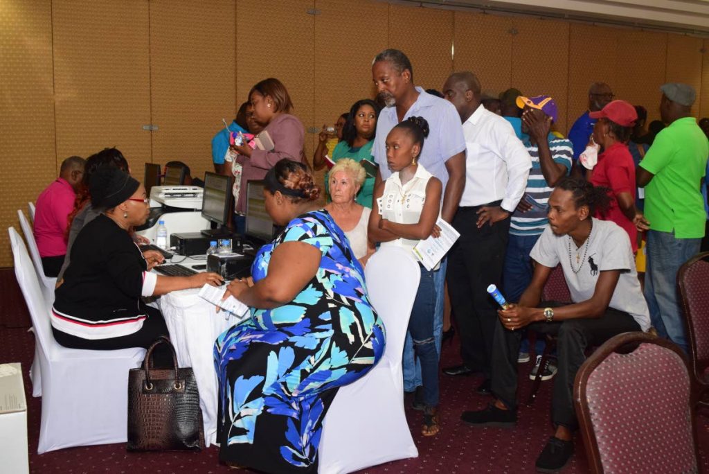 Residents listen to a THA official following last Monday’s public consultation on the voluntary acquisition of land for the $500 million new terminal building for the ANR Robinson International airport, as they wait to register for subsequent consultation sessions with a THA team.