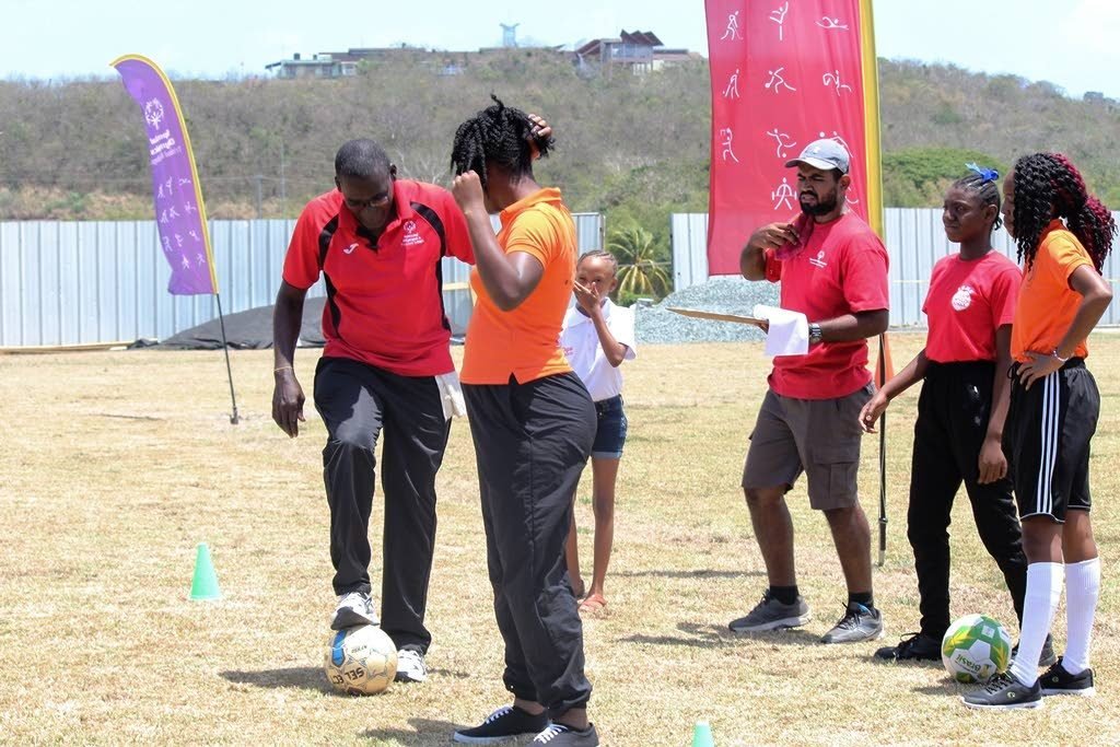 SOTT head football coach Fitzroy Edwards tests the ball before the start of the female individual football skills competition.
