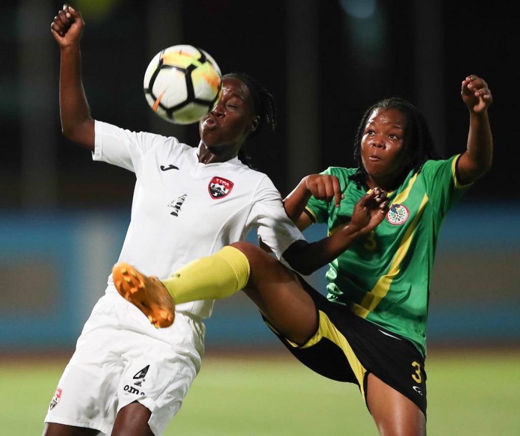 TT’s Rhea Belgrave, left, vies for the ball  with Dominica’s Alijah Tire during the CONCACAF Women’s Championship Qualifier at the Ato Boldon Stadium, Couva, recently.