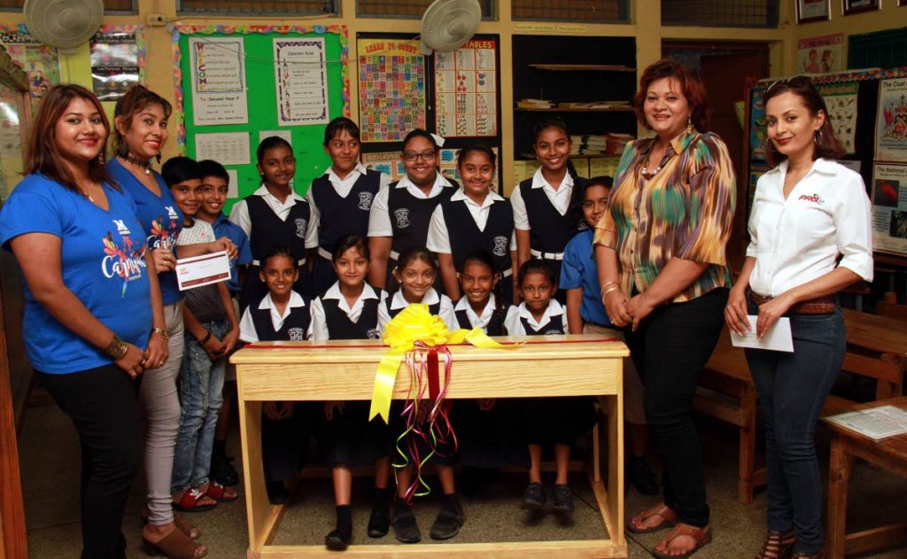 At center, happy students of the Debe Hindu Primary School seated on one of the 25 desk which was donated by Mario's Pizza and PROcom. At left, from Mario's Pizza Amrita Bajnath-Seepersad and Tracy-Ann Bagoo, at right, Marketing Manager of PROcom Asha Maharaj, second right, Principal of Debe Hindu School Usha Rampersad-Gokool.
PHOTO BY ANIL RAMPERSAD. 