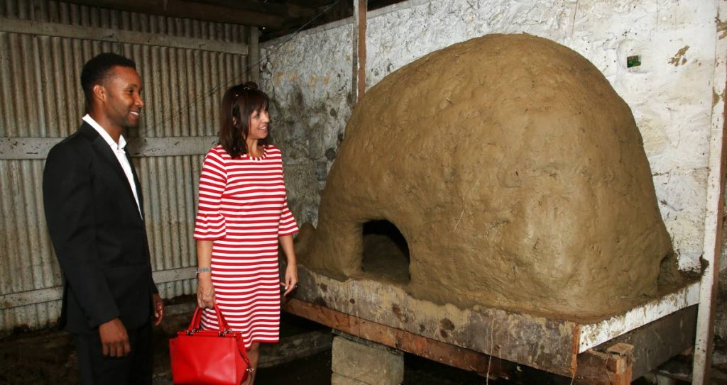 YESTERYEAR’S OVEN: Merikin Prince of Moruga Eric Lewis shows Deputy British High Commissioner Caroline Alcock a refurbished earthen oven which was used to roast cocoa, at the Cocoa Museum in Moruga on Saturday.