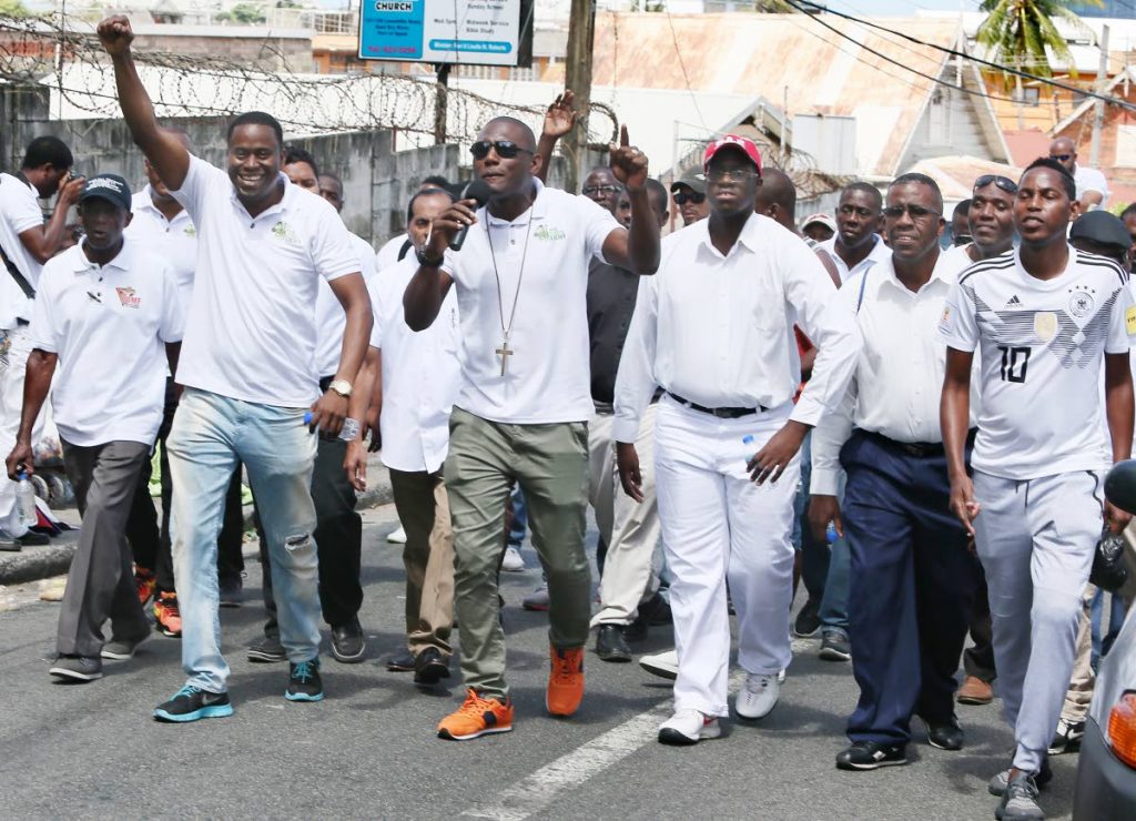 ALL FOR GOD: Members of The Lord’s Army, led by Christopher Roberts, 
march through Laventille to reach out to men.   PHOTO BY AZLAN MOHAMMED