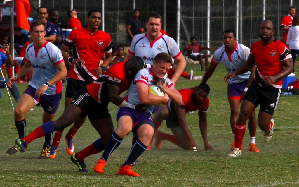 Bermuda’s Conor McGowen, centre, is tackled by TT’s Jason Quashie in their RAN 15s Tournament clash recently at St Anthony’s Ground, Westmoorings.