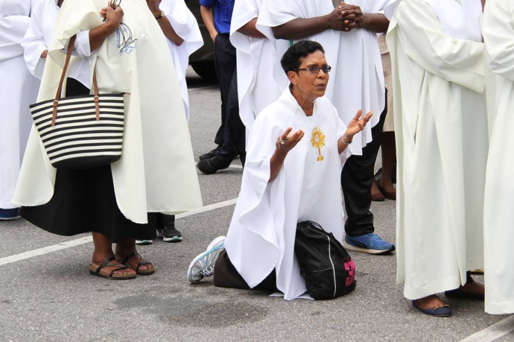 PRAYING: A woman kneels ouside the Cathedral of the Immaculate Conception as thousands celebrated Corpus Christi, yesterday. PHOTO BY SUREASH CHOLAI

