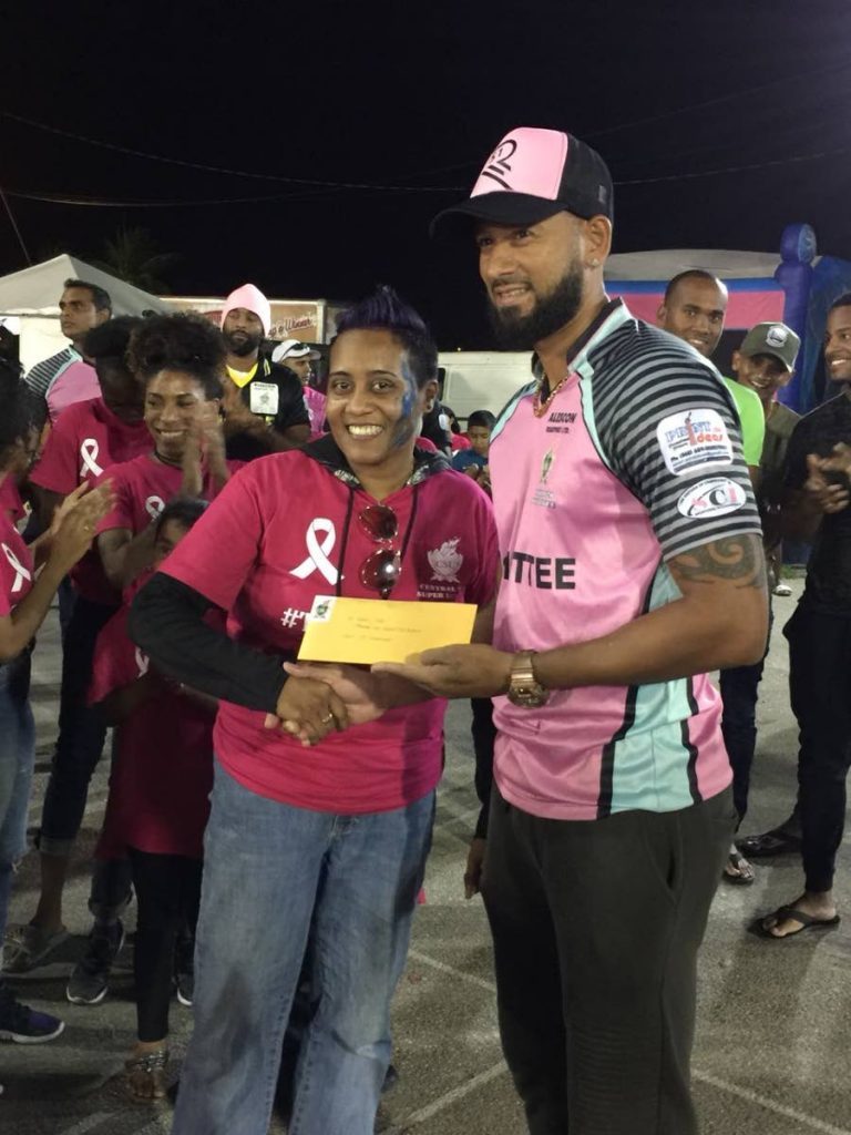 Cricketer Rayad Emrit, right, makes a donation to Koriella Espinoza of Korie’s Kids on Saturday after special jerseys were on sale on Saturday in the Central Super League to raise funds.