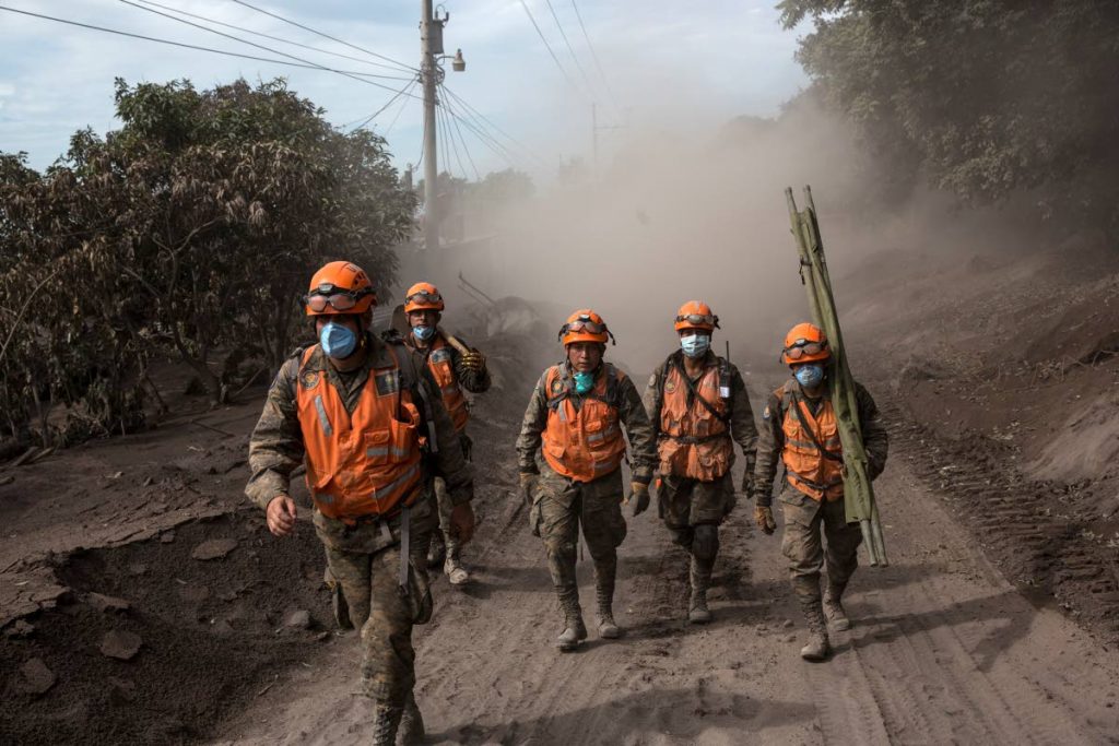 Rescue workers walk near the Volcan de Fuego in El Rodeo, Guatemala yesterday. AP PHOTO