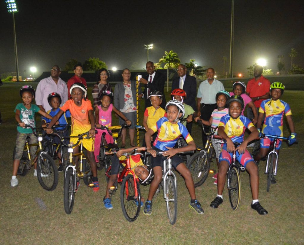 Minister of Public Utilities, Robert Le Hunte (back row, centre), switches on the lights at its commissioning at the Arima Velodrome. Looking on are Minister of Education Anthony Garcia; Mayor of Arima Lisa Morris-Julian; Deputy Permanent Secretary of Public Ultilities, Beverly Khan; officials of TTEC and cyclists from Madonna Wheelers.
